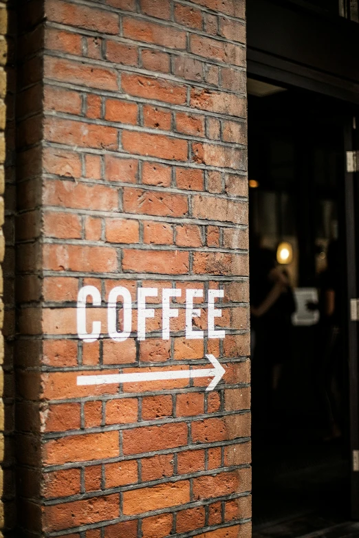 a brick wall with a sign stating that there is coffee outside of it