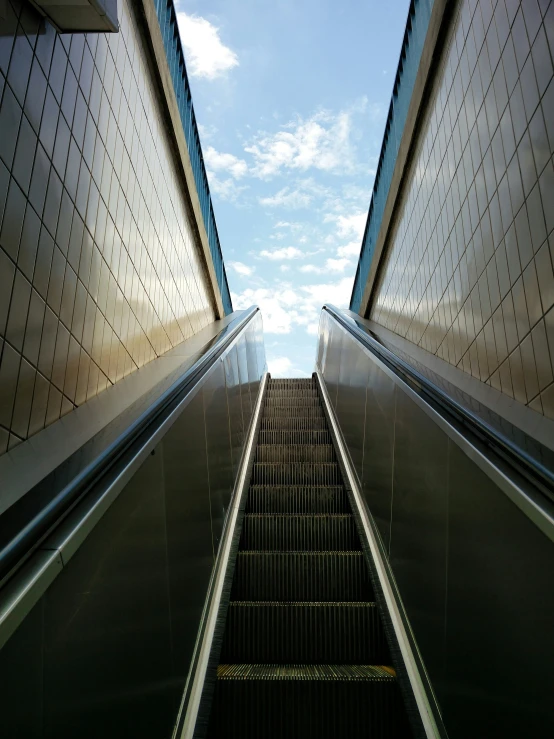escalators inside of a building with a sky view