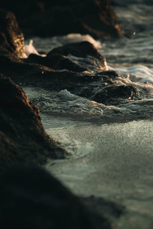 the rocks are sitting in the water next to the shoreline