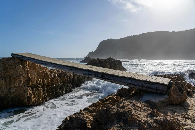 an old broken wooden bridge crosses the ocean