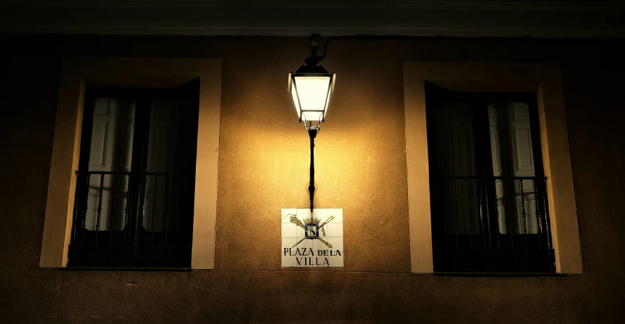 a lamp shines next to two windows in a dark building