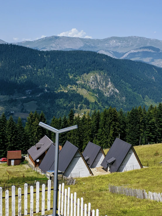 a white fence and houses near mountains and hills