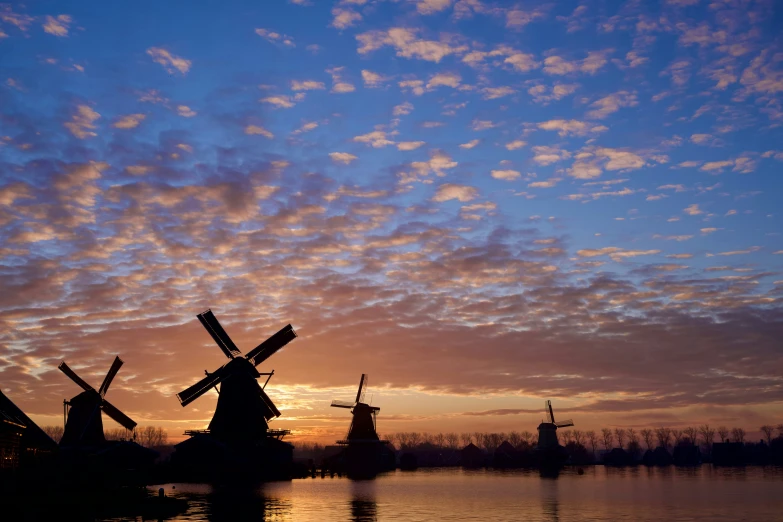 a couple of windmills on the ocean during sunset