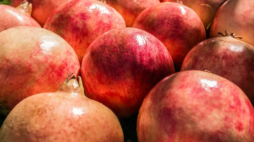 a group of red pomegranates stacked together on the ground