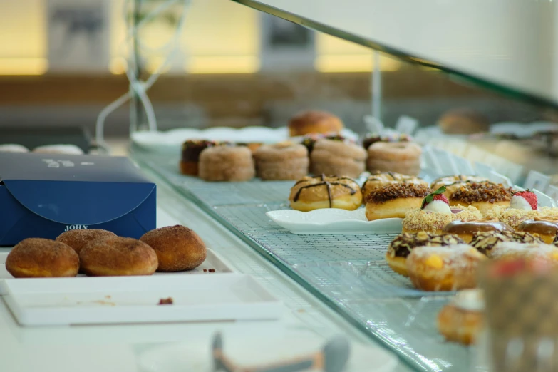 many different types of donuts on display behind a glass case