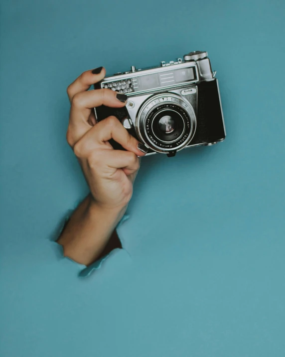 a hand holding a camera over a blue background