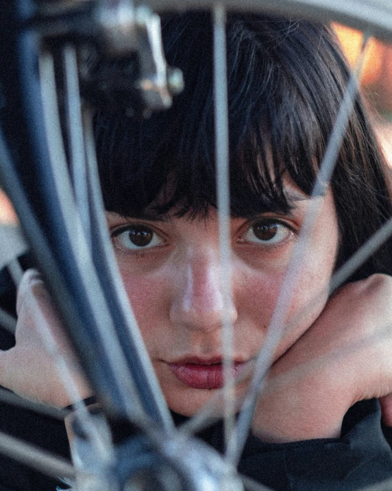 a woman sitting behind a bike while leaning on her hand