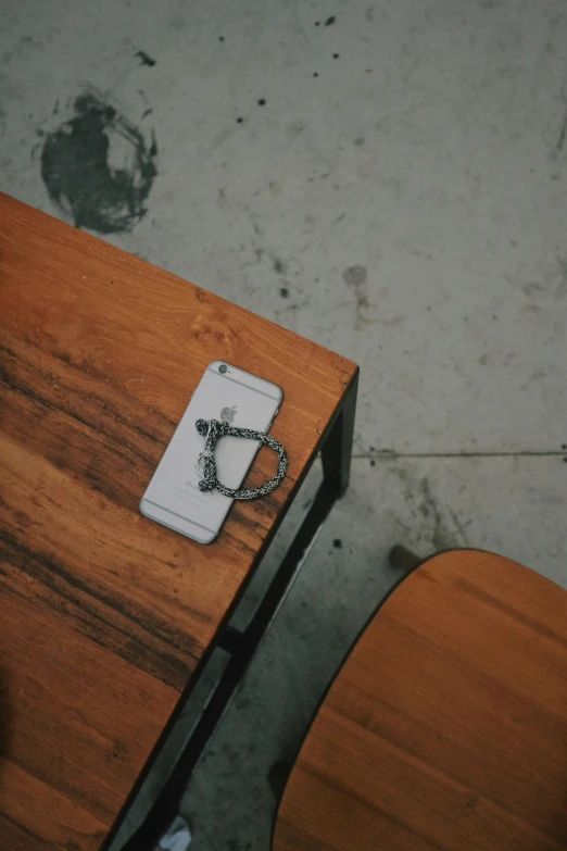 small white pendant with a charm hanging from it on a wood table