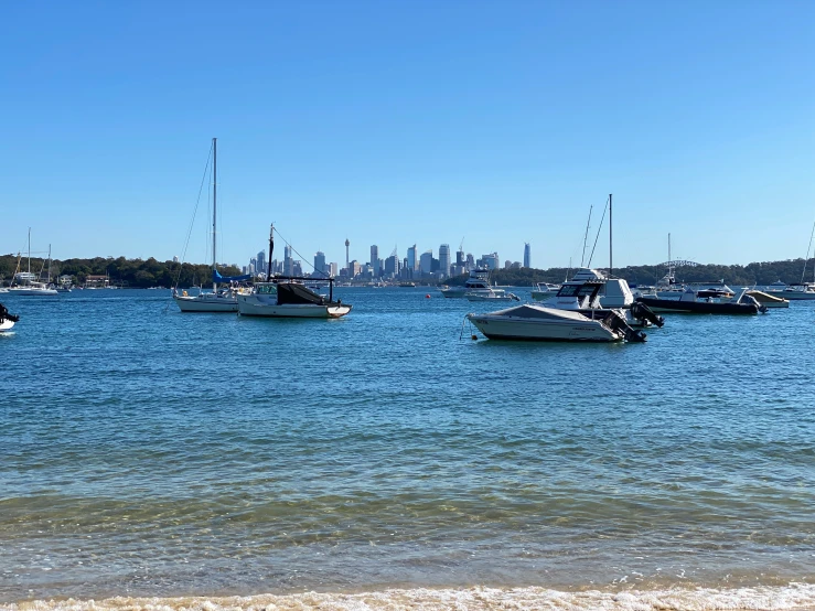 many boats are sailing on the water with a city in the background