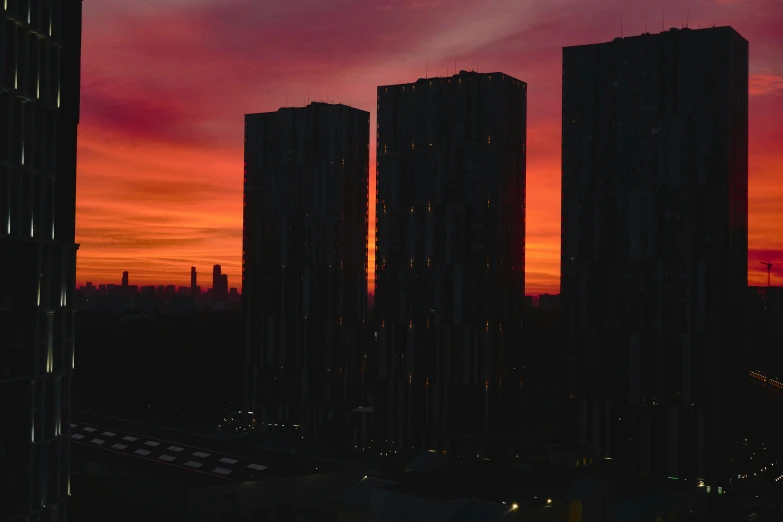 some very large buildings and orange clouds in the sky