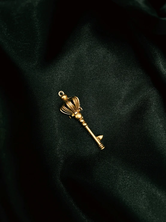 a golden pin on a black fabric with a cross on it