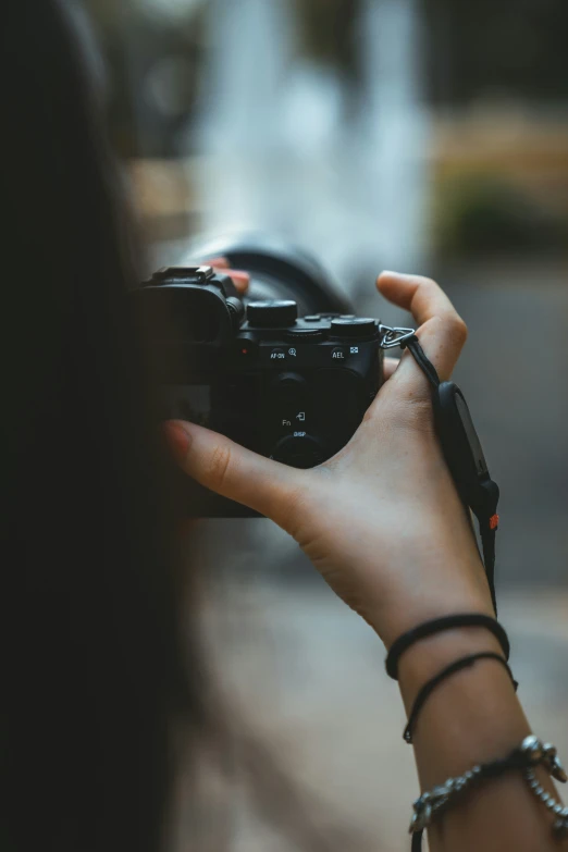 someone holding a black camera over a street