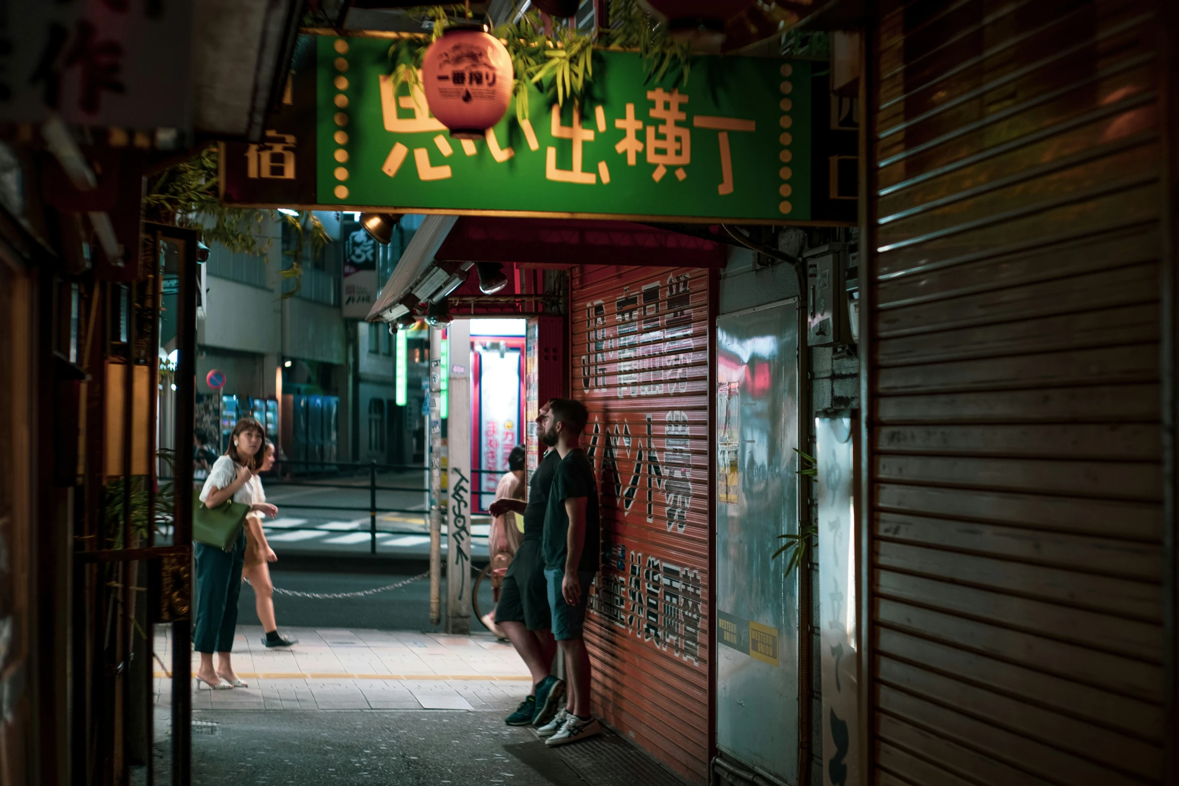 people standing in front of a restaurant called sushi on the street