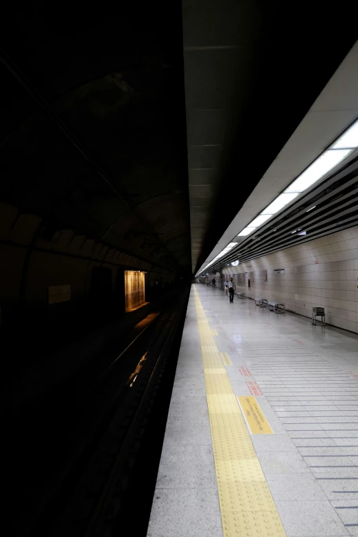 a long subway platform at night with one person walking past it