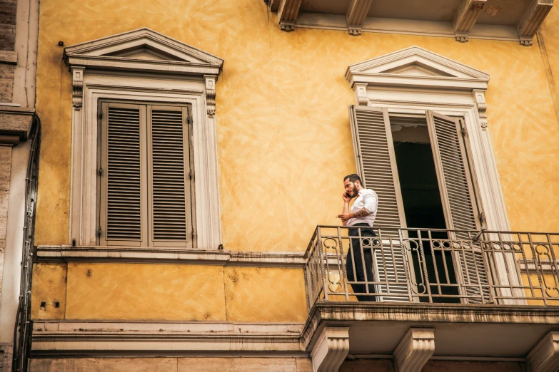 a man is on his cell phone while standing on a balcony