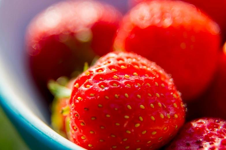 three strawberries are sitting in a blue bowl