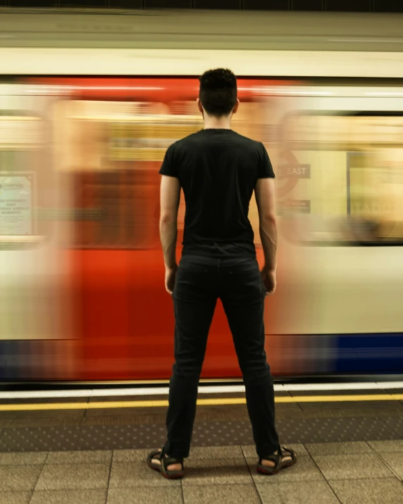 a man standing in front of a train that has blurred red and blue lines