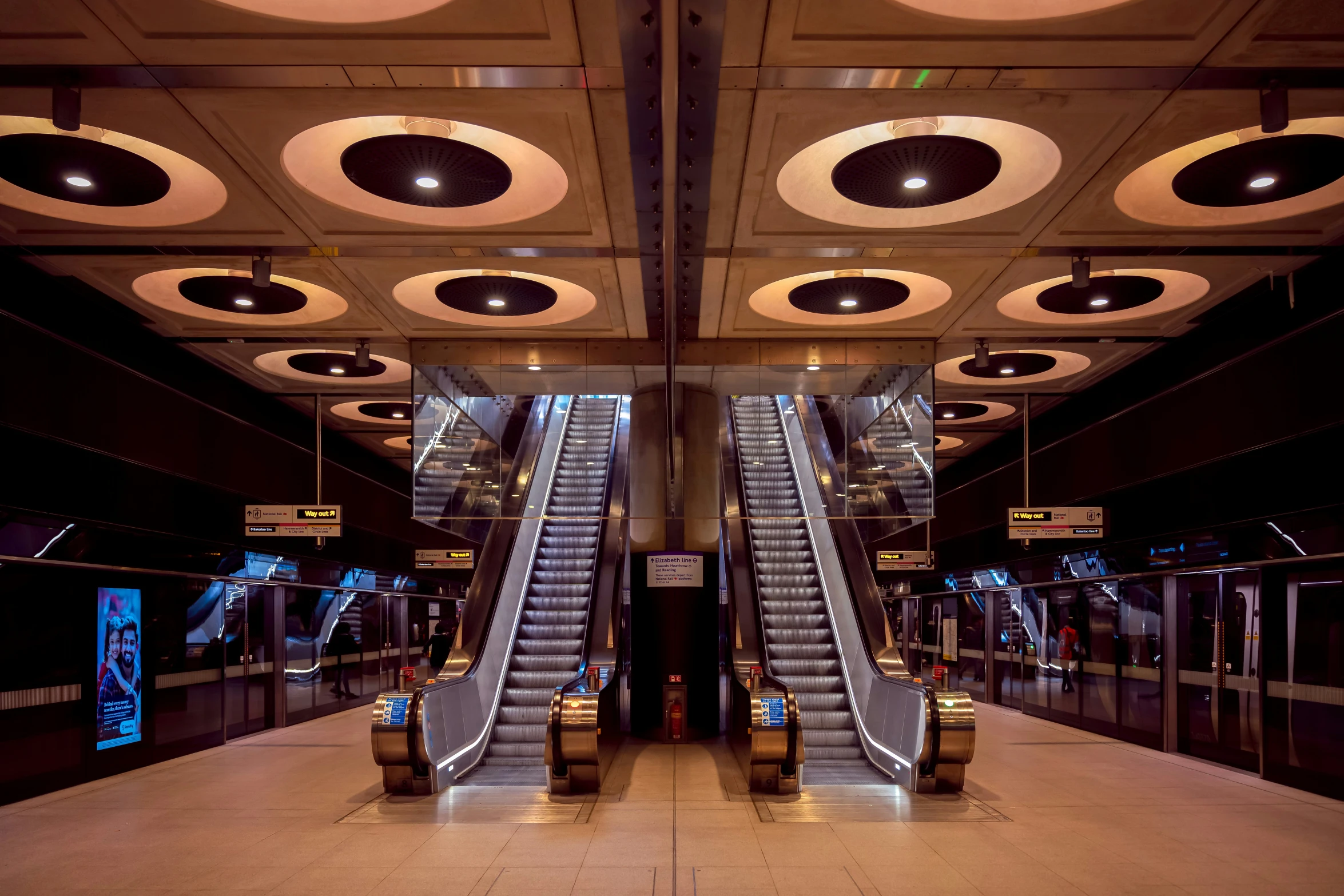 two escalators in an airport with multiple circular lights