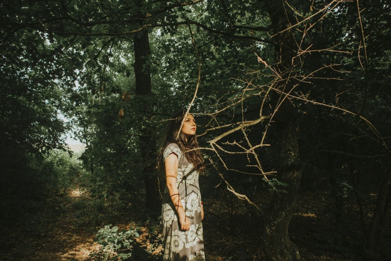 a woman is standing in the woods holding on to a nch