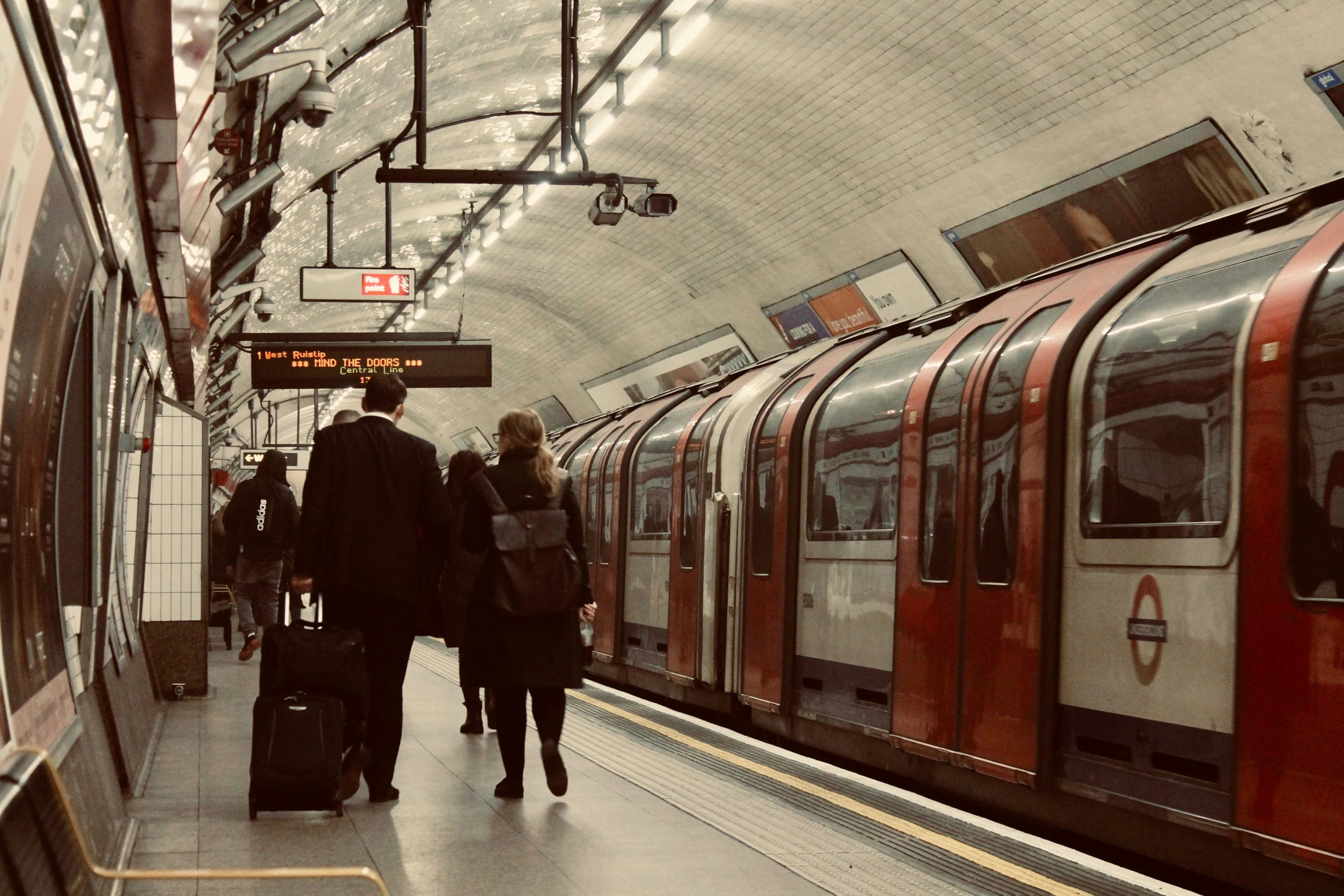 people are walking along with their luggage at a subway station