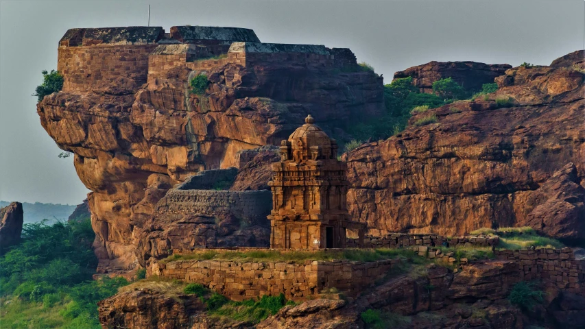 a large mountain side tower is surrounded by greenery