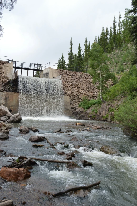 a small waterfall with people sitting on the platform above