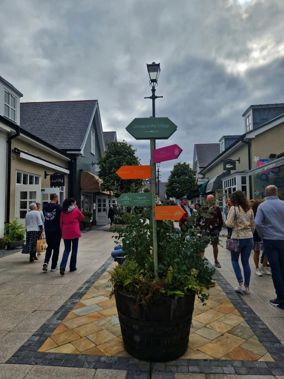 many people walk down an empty sidewalk with a potted plant