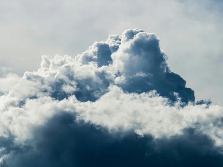 the plane flies high in the cloudy sky