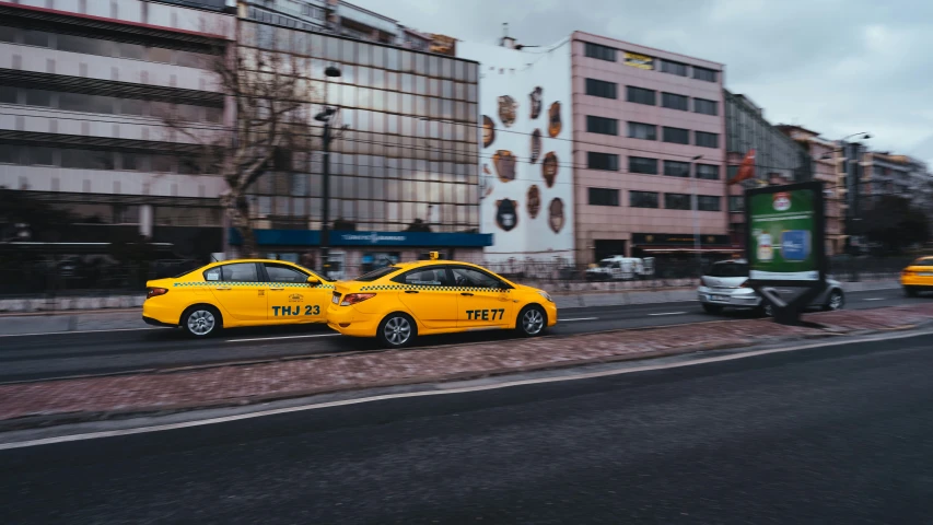 the cabs are on the street and the woman is riding the scooter