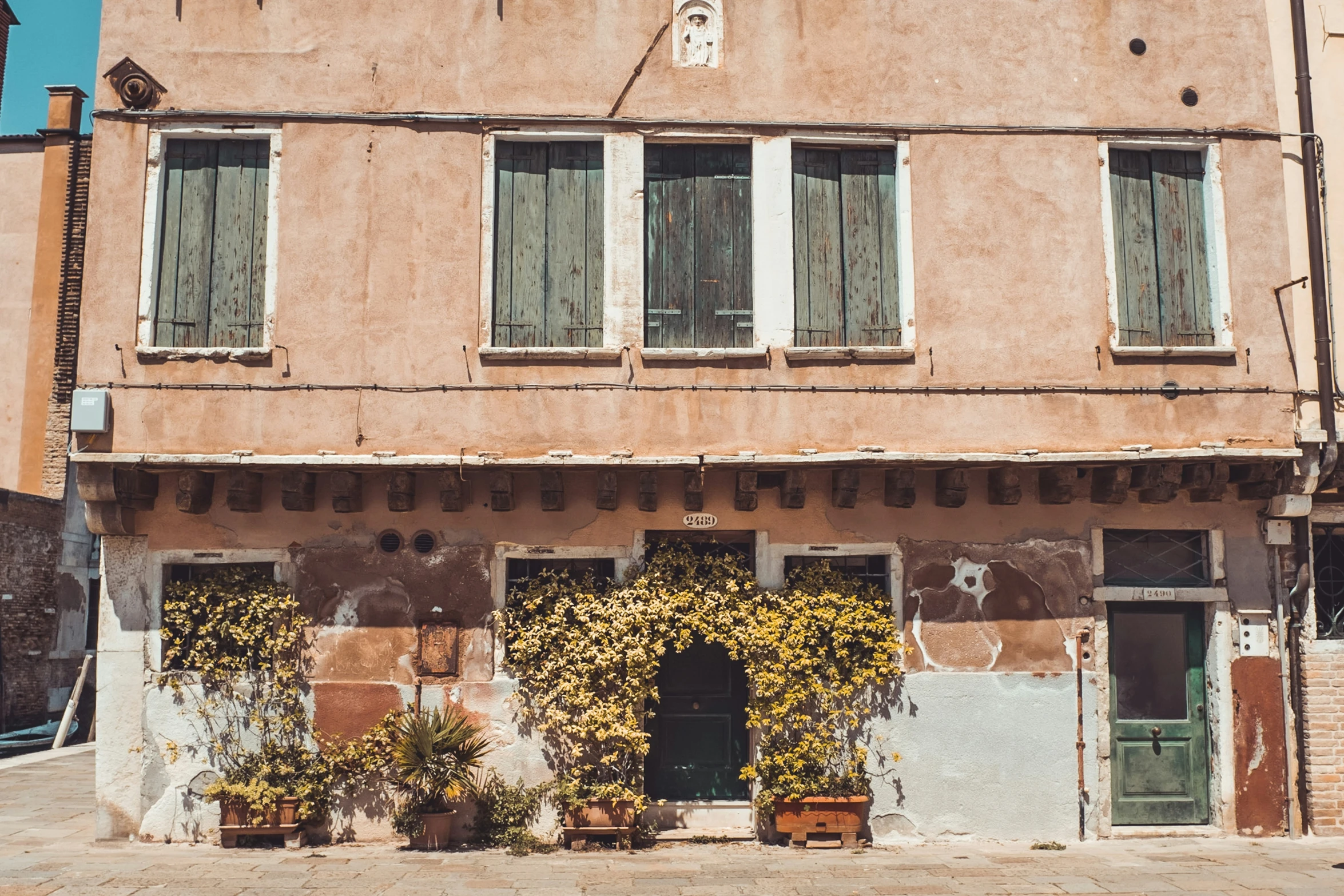 a three story building that is next to some plants