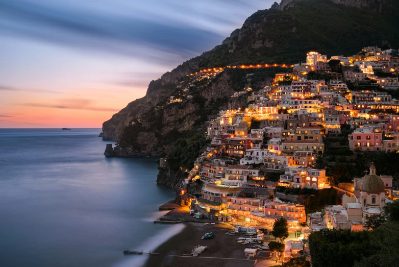 a night time city on a cliff above the ocean