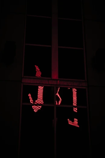 a window reflecting some dark red light at night