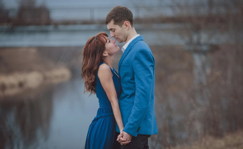 the man and woman are kissing in front of the water