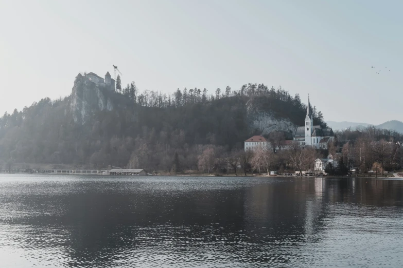 a church by a mountain side sits on a lake