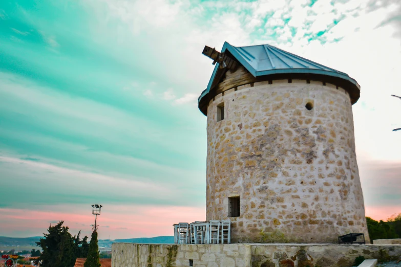 an old tower sits on a stone ledge near a building