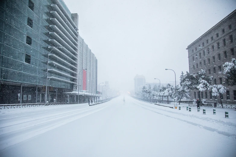 the city street with several buildings covered in a snowstorm