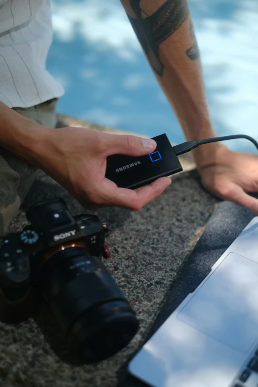 a person is holding a camera next to a laptop