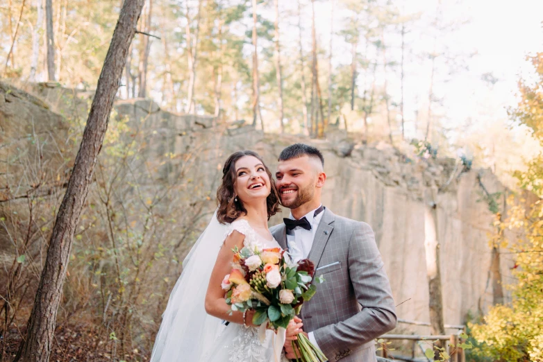 a newly married couple pose for a po in the woods