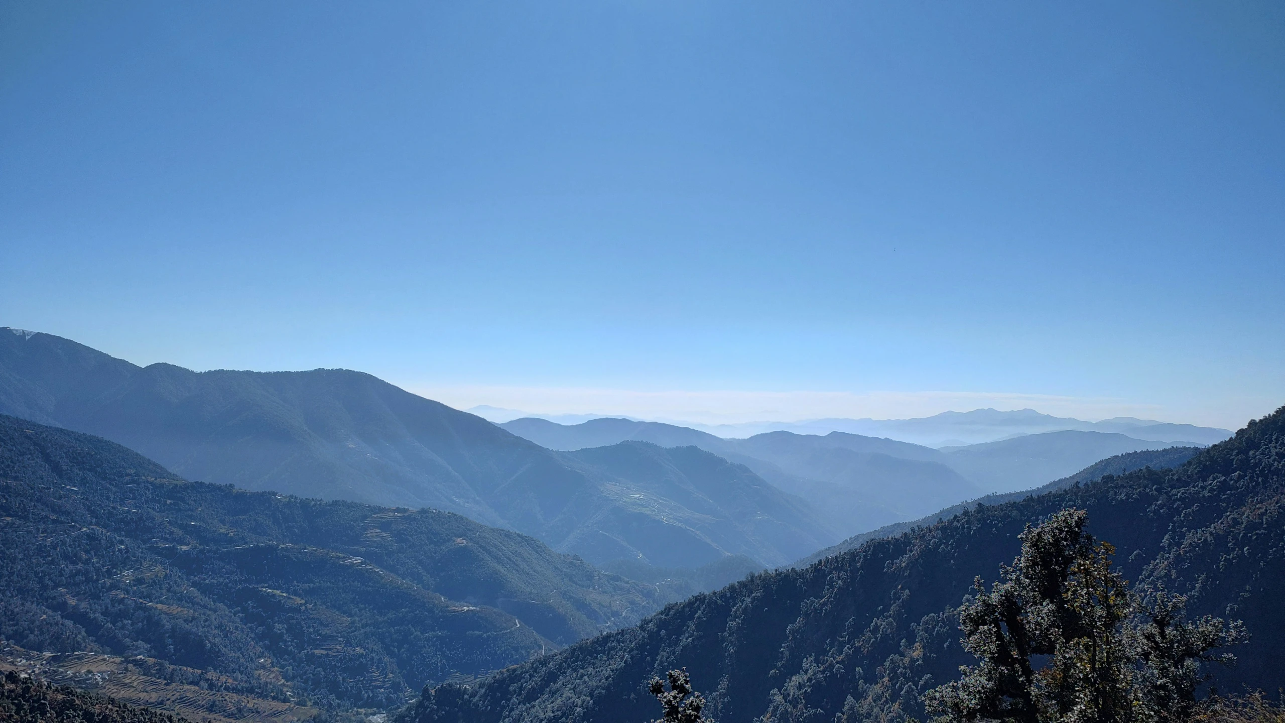 two people sitting on a bench in the mountains