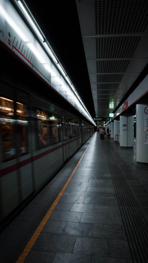 a dark subway station with train coming up the platform