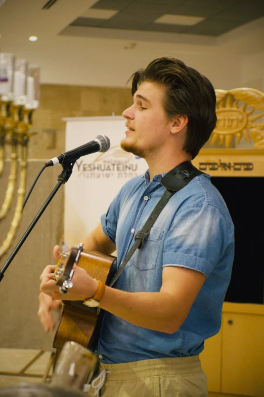 a man holding an acoustic guitar while standing in front of a microphone