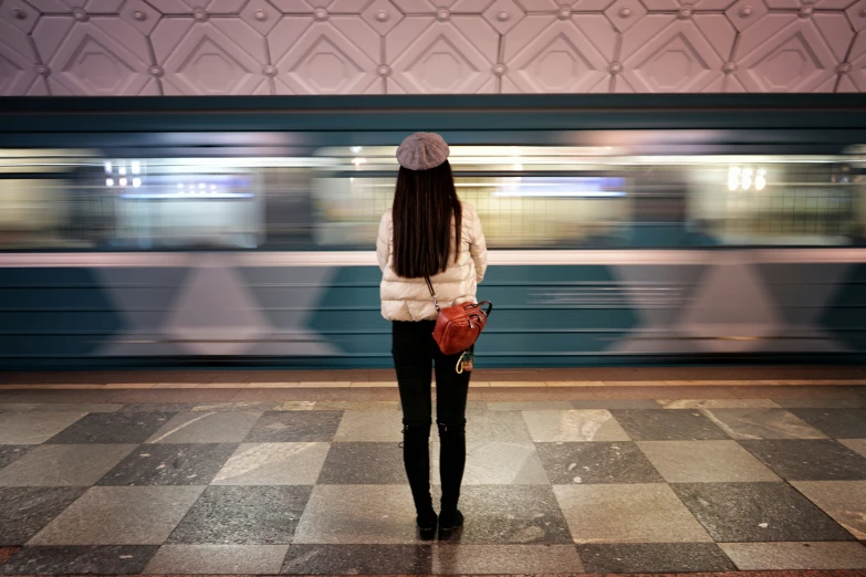 a woman standing on the platform looking at a train