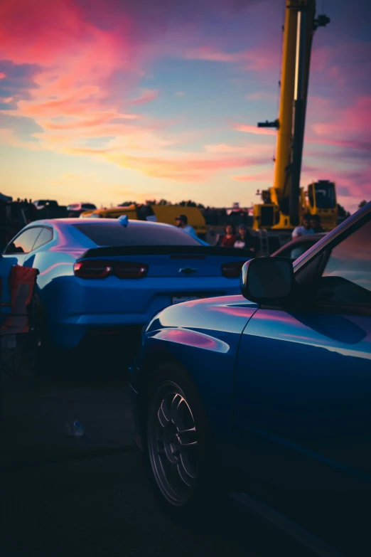 two cars parked in front of a large crane