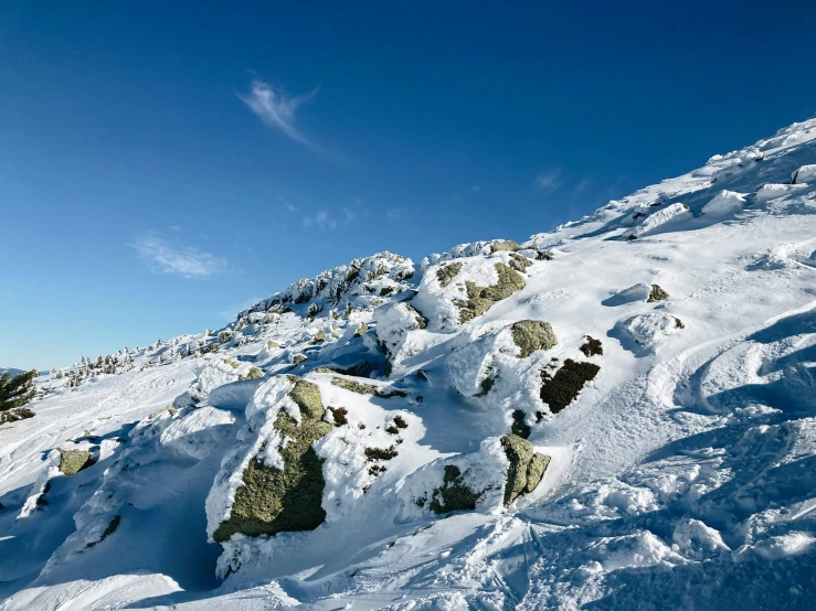 a snowboarder jumps off the edge of a snowy mountain