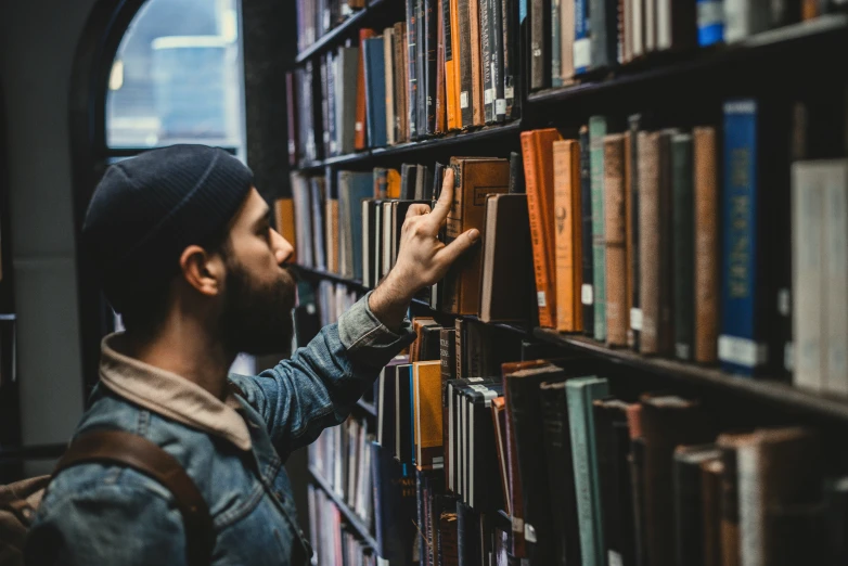 man picking a book off the shelf in a liry