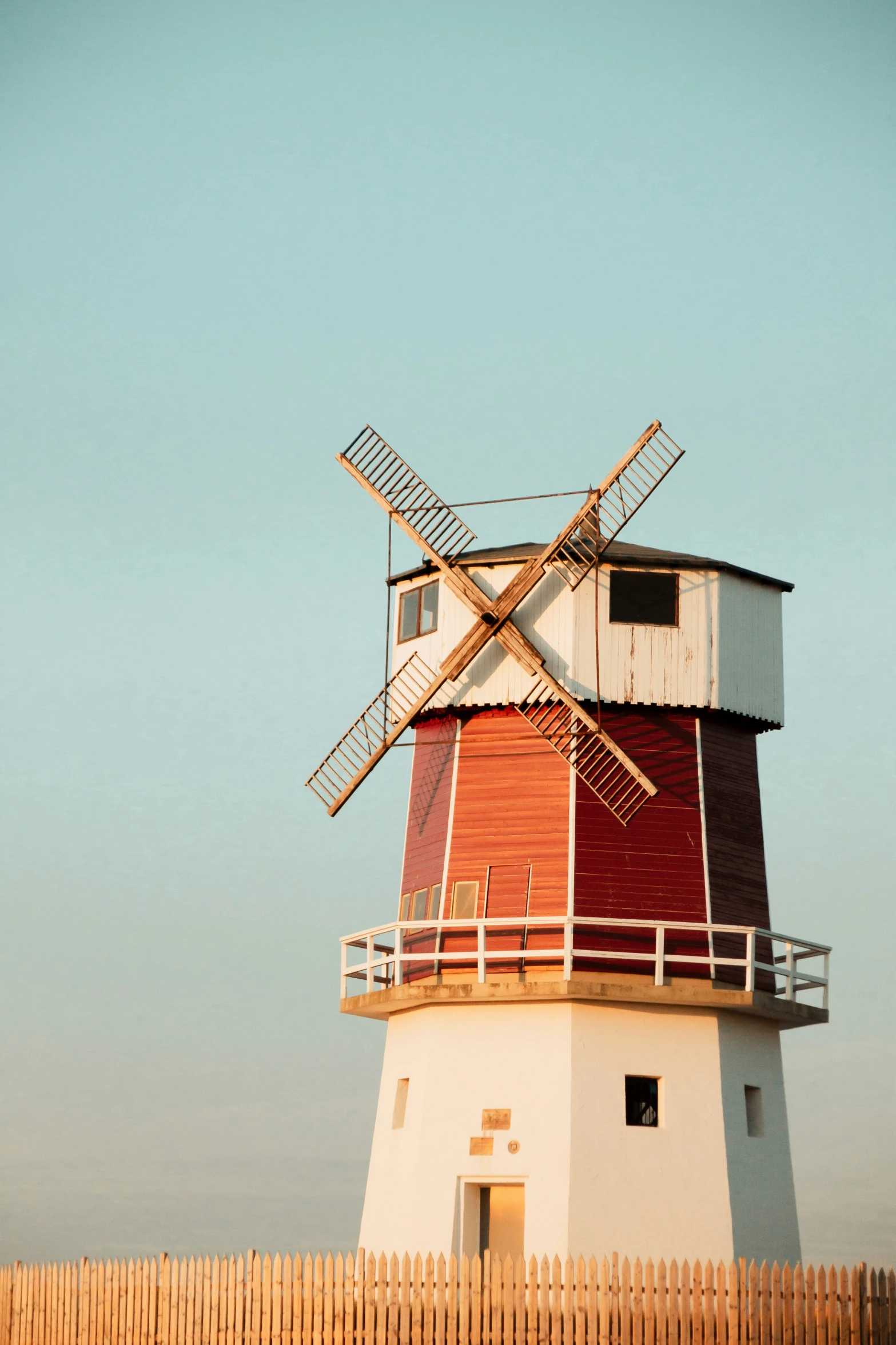 a windmill is perched next to a fence