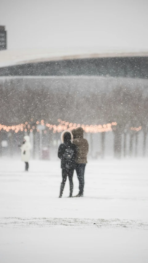 two people standing in the snow at night