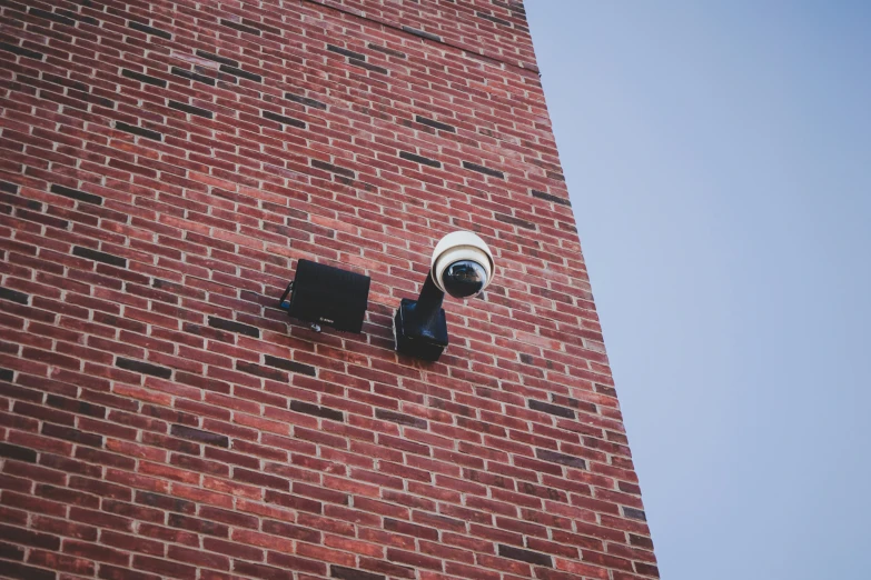 a security camera mounted to the side of a brick building