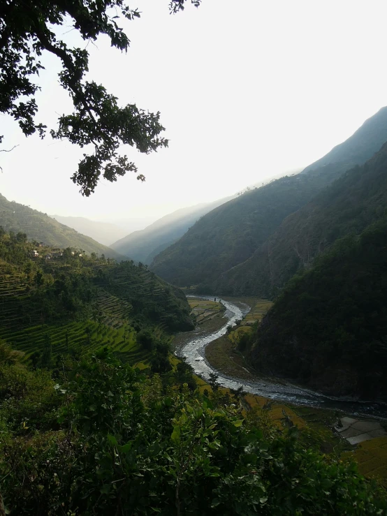 a river surrounded by hills and trees near the bottom of a hill