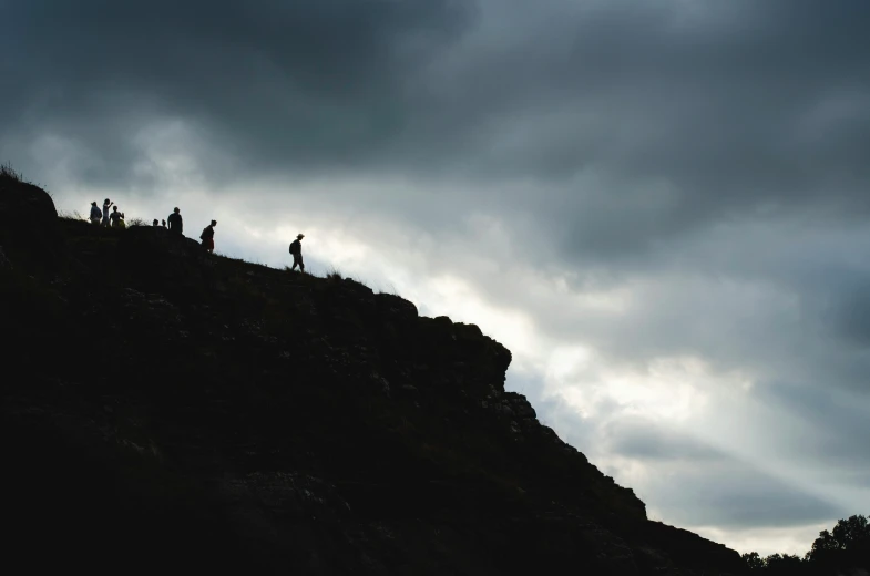 two people stand at the top of a hill under an ominous sky